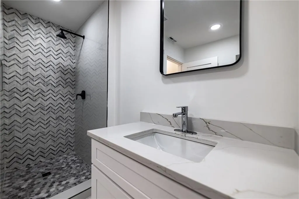 Bathroom with vanity, a tile shower, and recessed lighting