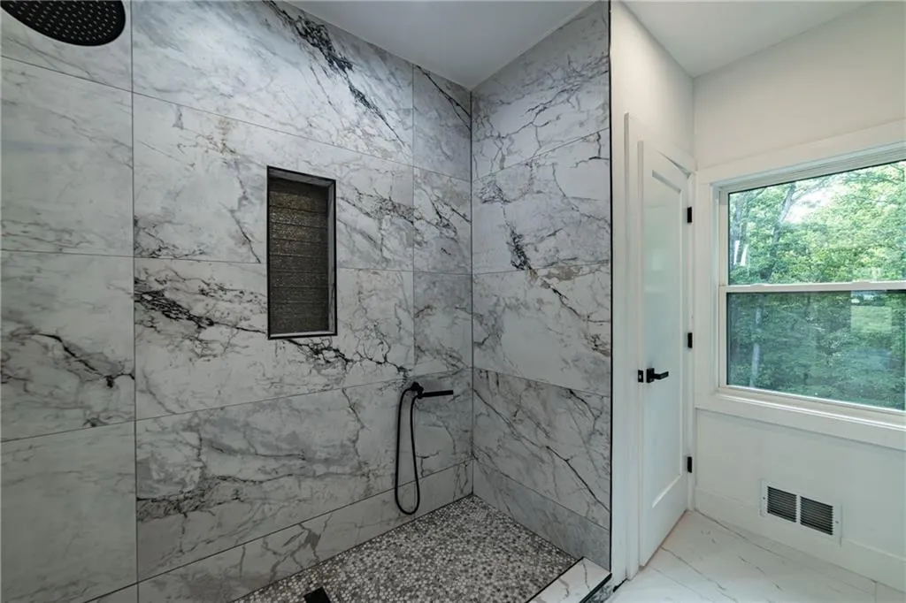 Full bath with a marble finish shower and marble finish floors