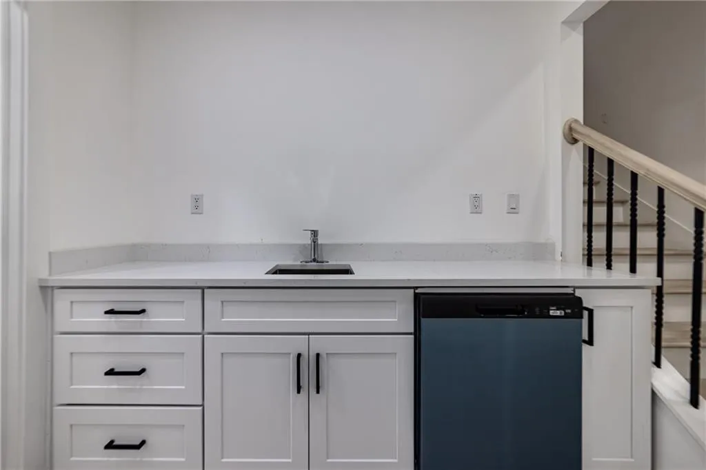 Kitchen with dishwashing machine, light countertops, and white cabinets