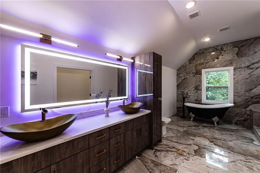 Full bathroom featuring marble tiled floors, lofted ceiling, double vanity, a soaking tub, and recessed lighting