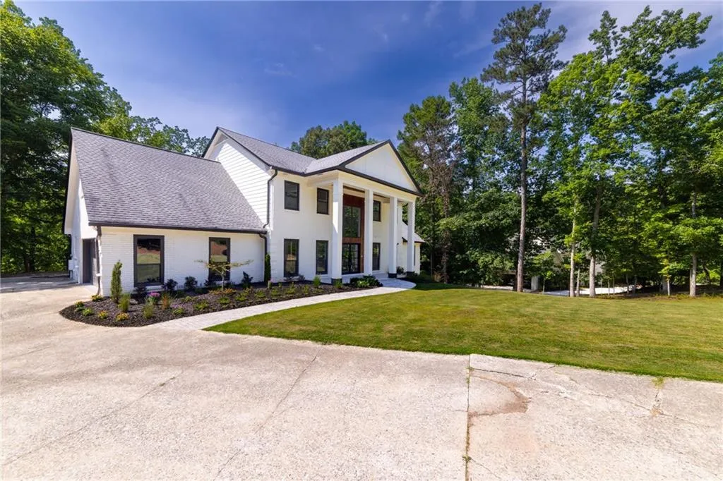 Greek revival inspired property with a front yard, roof with shingles, concrete driveway, brick siding, and a garage