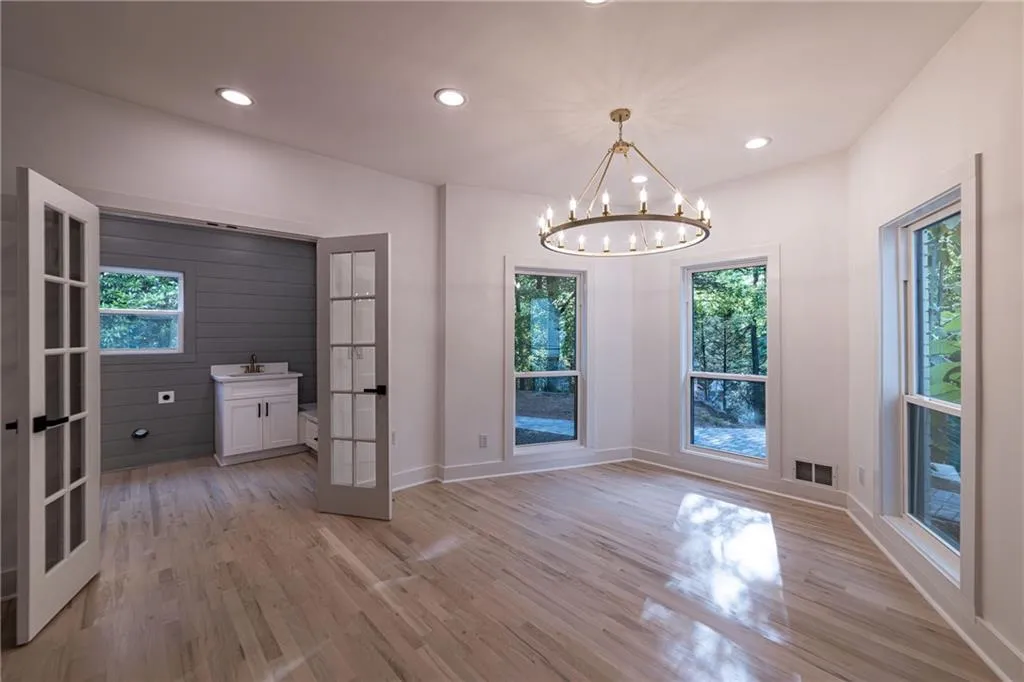 Unfurnished dining area featuring french doors, recessed lighting, light wood finished floors, and a chandelier