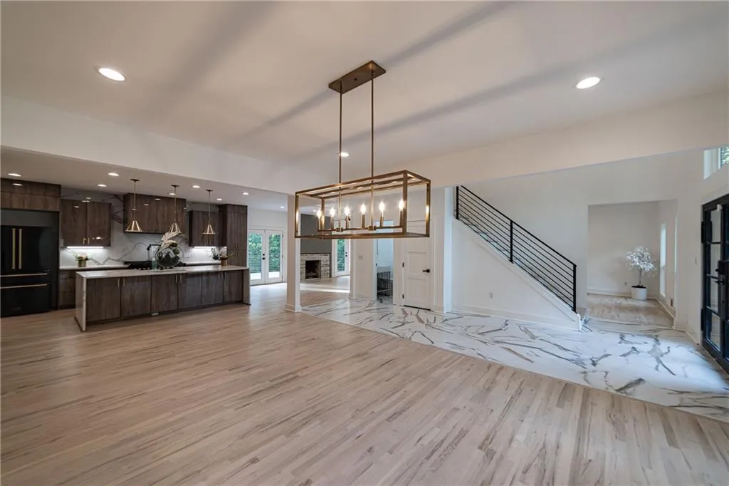 Unfurnished living room featuring a fireplace, recessed lighting, stairs, light wood-style floors, and a chandelier
