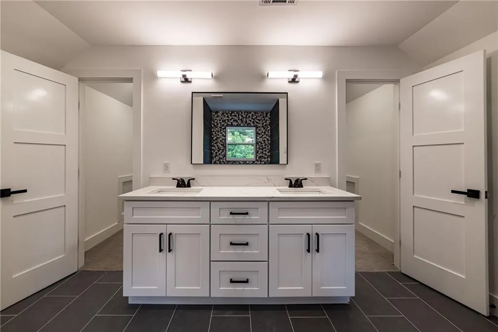Full bathroom with tile patterned floors, double vanity, and lofted ceiling