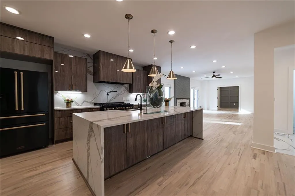 Kitchen featuring decorative backsplash, high end black refrigerator, recessed lighting, ceiling fan, and a spacious island