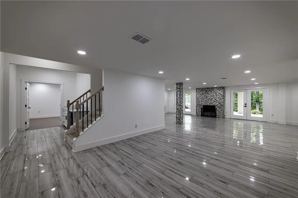 Unfurnished living room with recessed lighting, stairway, wood finish floors, and a large fireplace