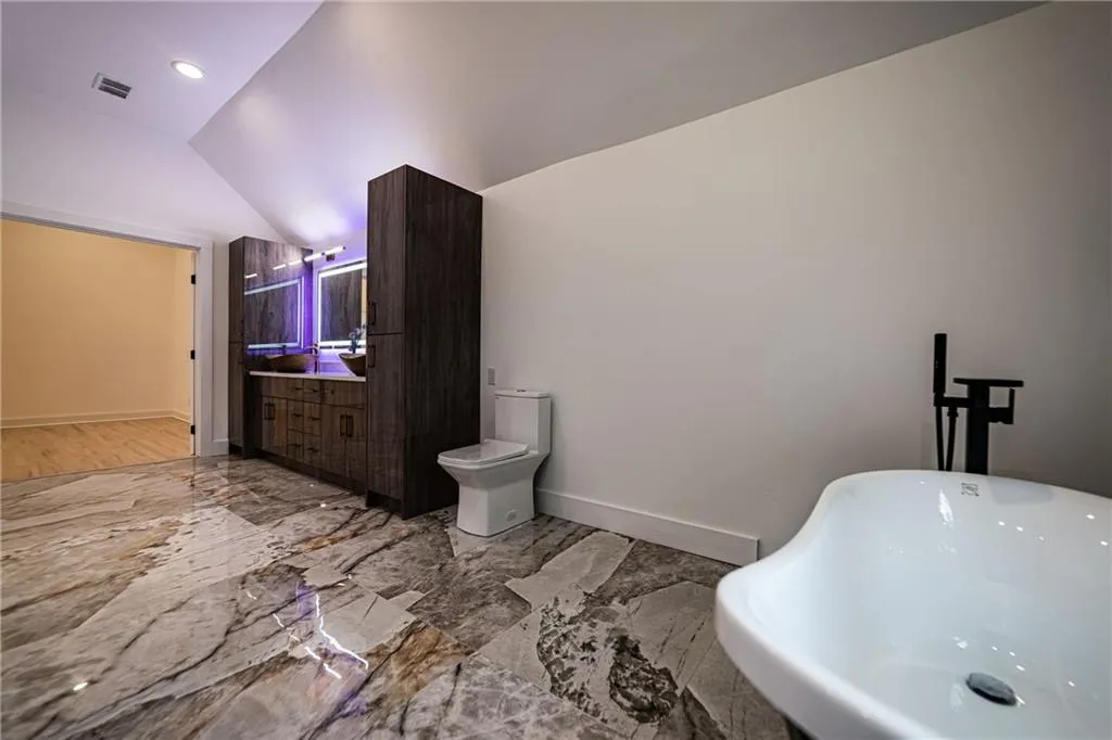 Bathroom featuring a freestanding tub, marble tiled floors, vaulted ceiling, and vanity