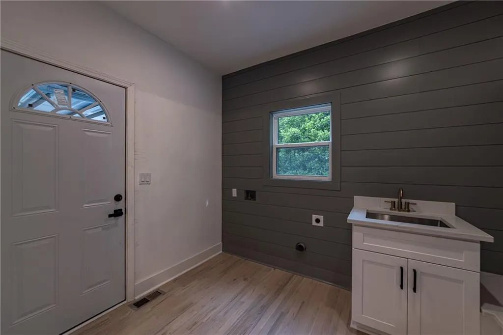 Washroom featuring electric dryer hookup, wooden walls, and light wood-style floors