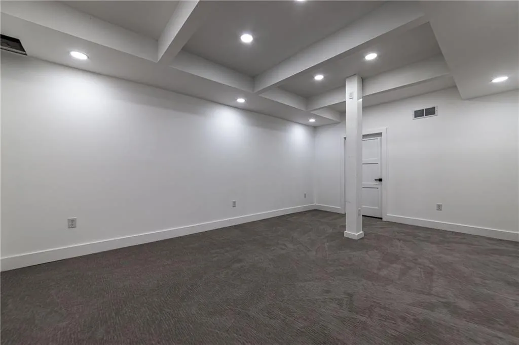 Finished below grade area with dark colored carpet and recessed lighting
