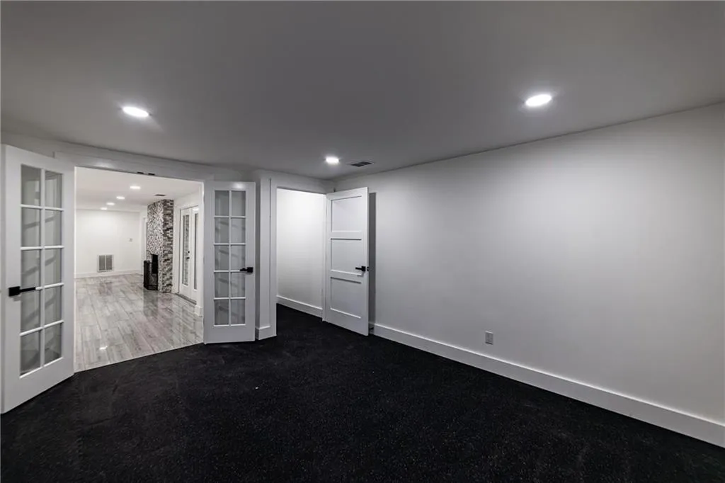 Unfurnished room with french doors, dark colored carpet, and recessed lighting