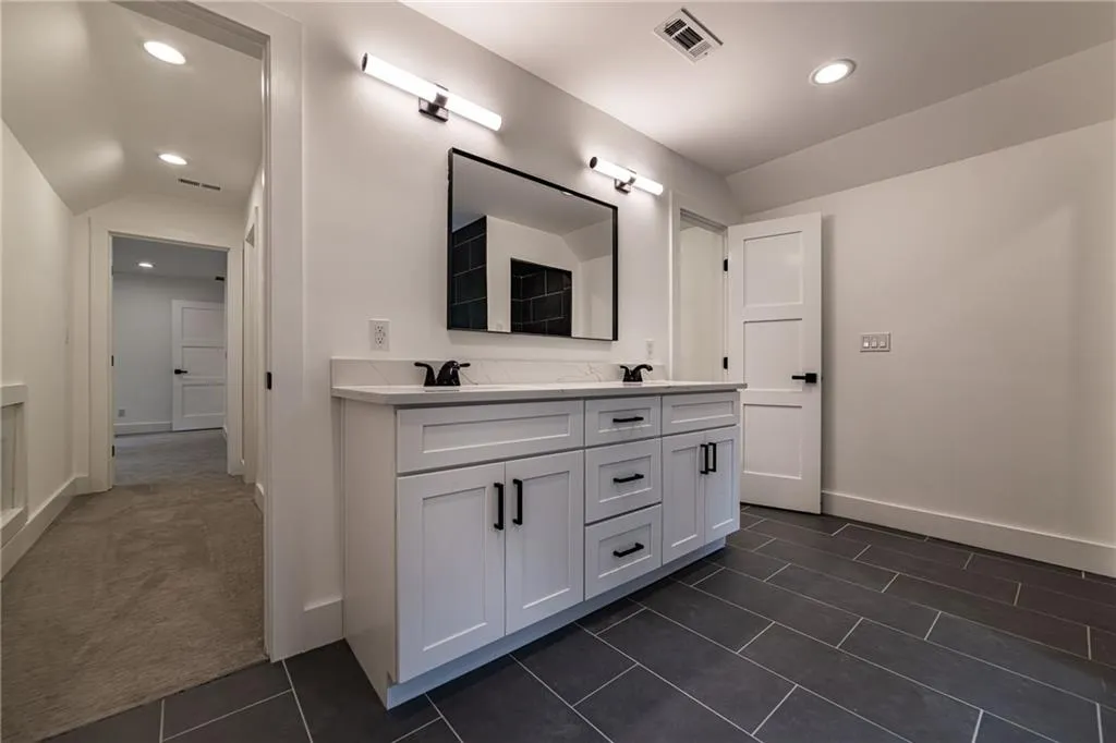 Bathroom with double vanity, recessed lighting, vaulted ceiling, and tile patterned flooring