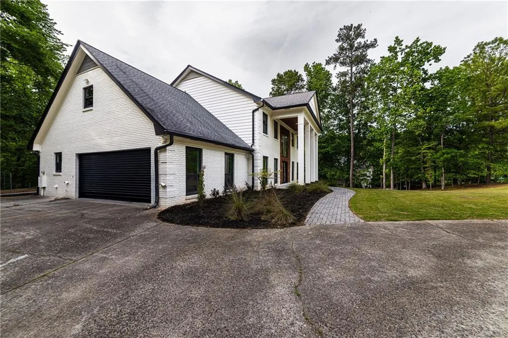 View of front facade with concrete driveway, brick siding, a front yard, and roof with shingles