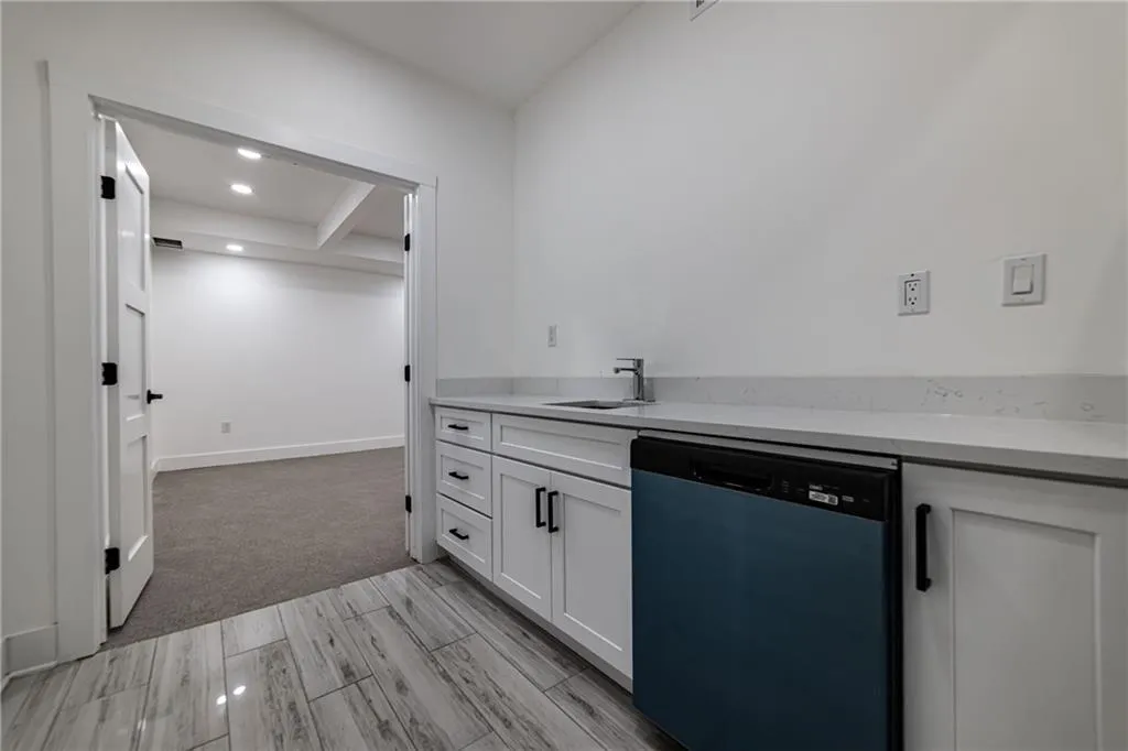 Kitchen with dishwasher, white cabinetry, light countertops, recessed lighting, and light carpet