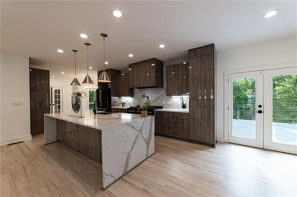 Kitchen featuring modern cabinets, french doors, light wood-type flooring, backsplash, and a spacious island