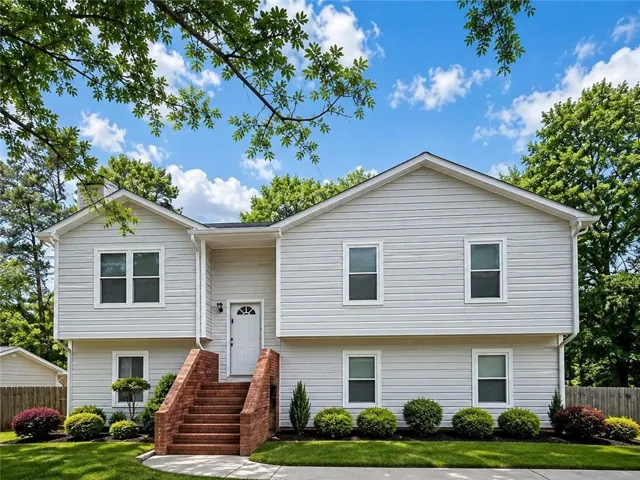 Split-level exterior with light-colored siding, brick entryway stairs, and a white front door with an arched window