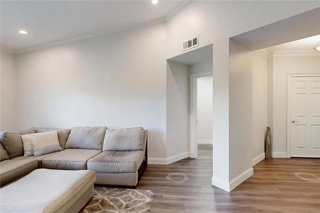 Living area with wood finished floors, crown molding, and recessed lighting
