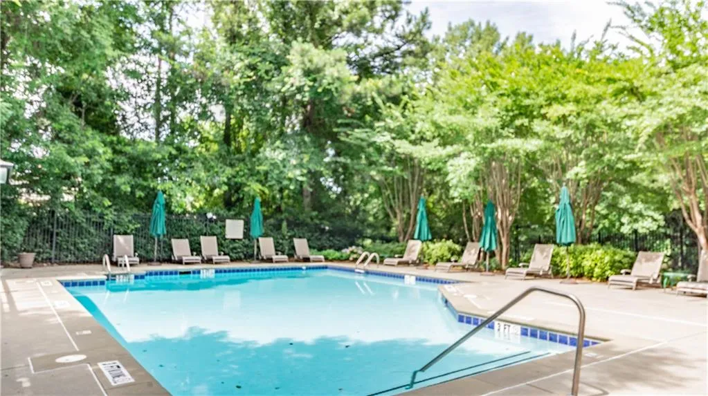 Community pool with view of wooded area and a patio
