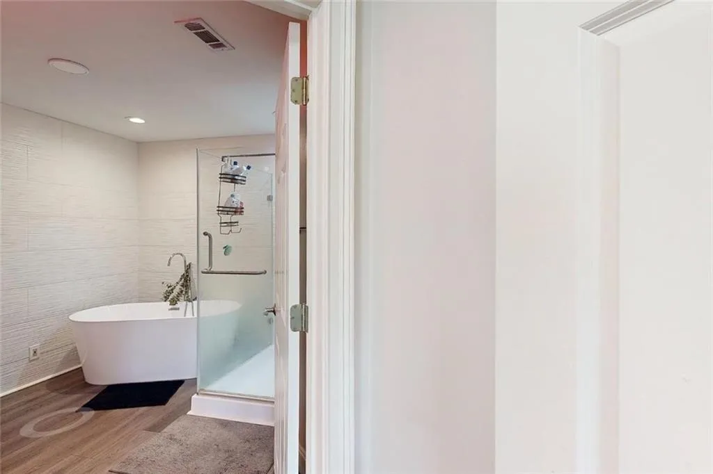 Full bath featuring wood finished floors, a freestanding bath, a stall shower, and recessed lighting