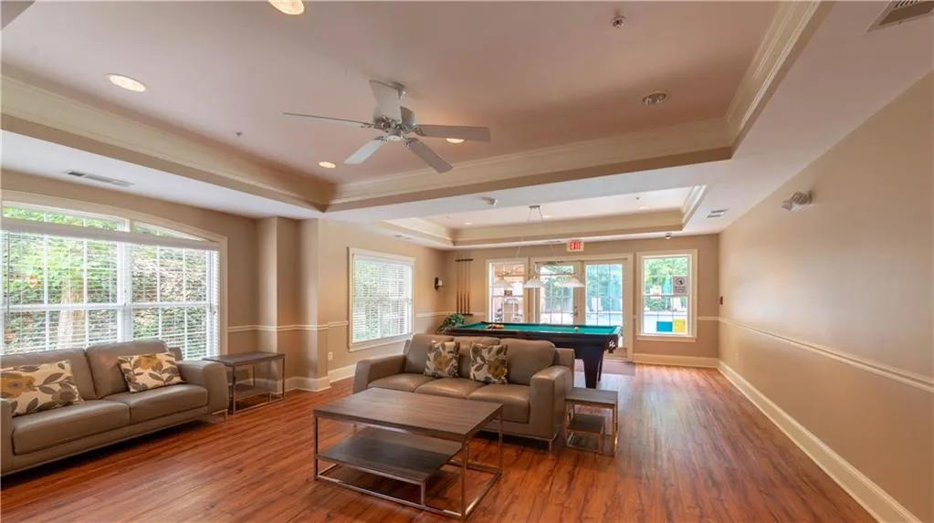 Living area with a raised ceiling, billiards table, wood finished floors, a ceiling fan, and crown molding