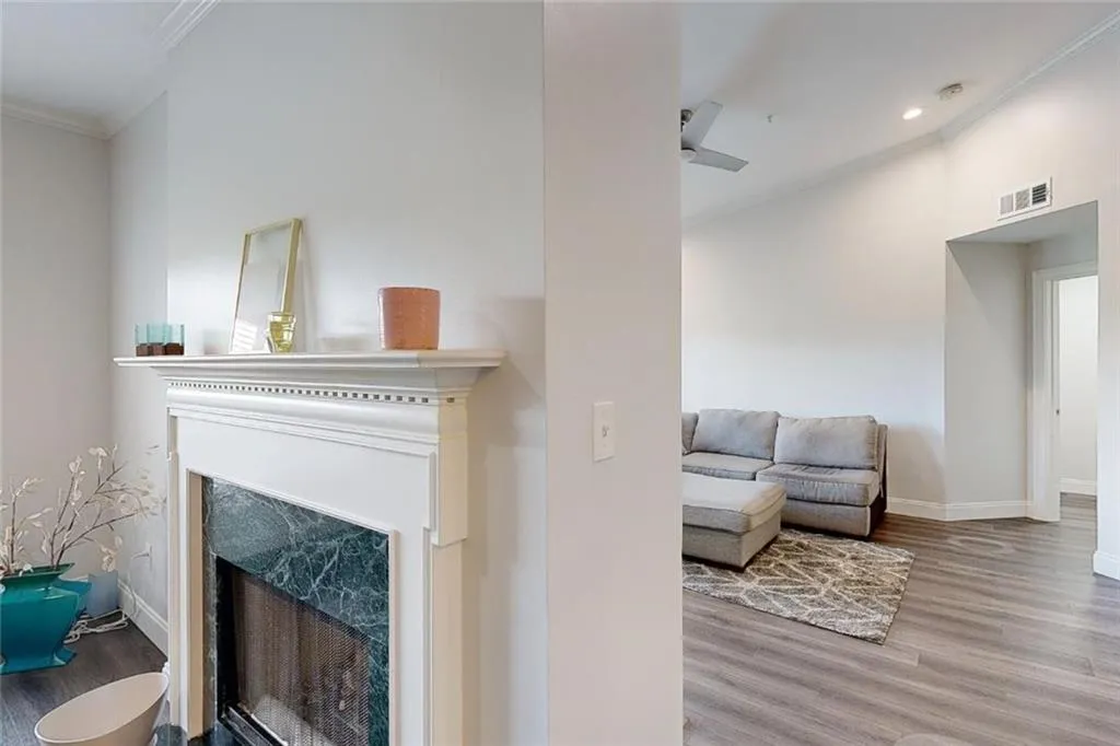 Living room with wood finished floors, ornamental molding, a high end fireplace, and recessed lighting