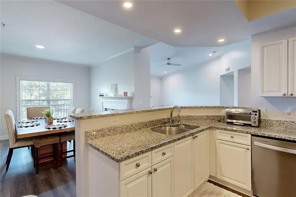 Kitchen with dishwasher, light stone counters, wood finished floors, a peninsula, and ceiling fan