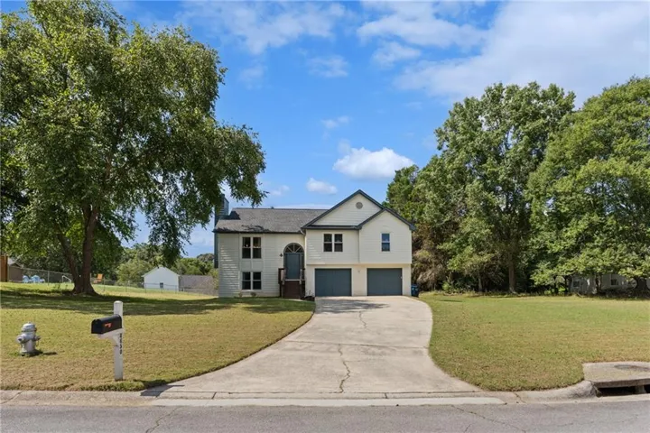 Two-story property with a light-colored exterior, an arched entry door, two garage doors, and a paved driveway