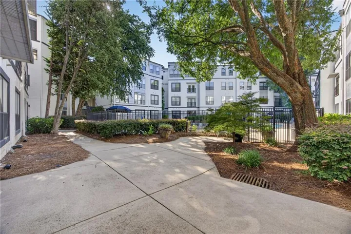Landscaped courtyard featuring mature trees, manicured hedges, and a paved pathway