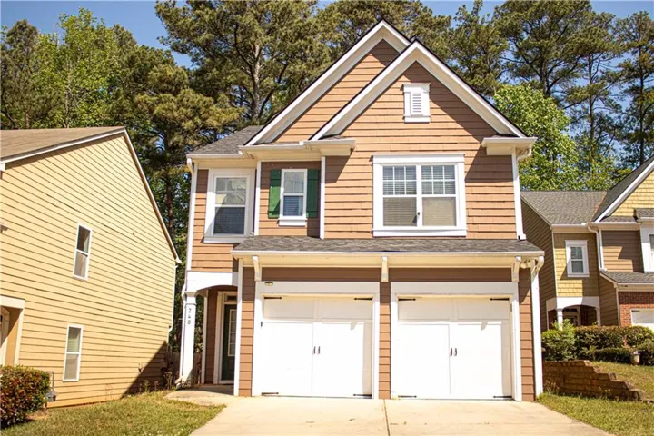 View of front of property with driveway, an attached garage, and roof with shingles