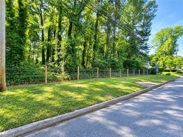 Manicured green lawn with a wire fence and mature trees