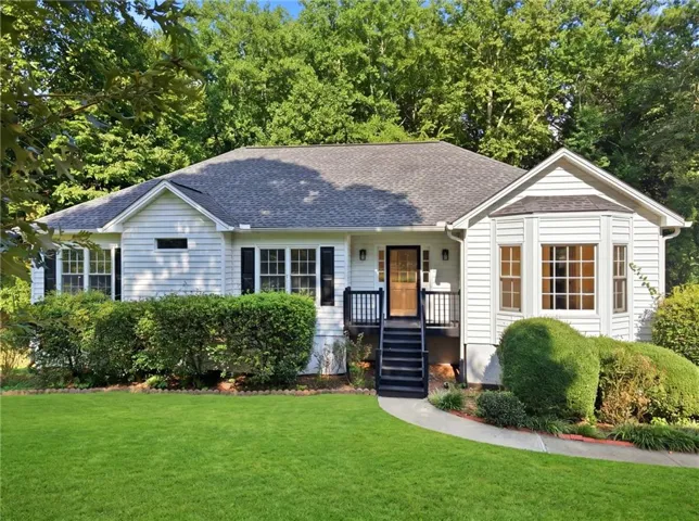 White siding exterior with a dark shingled roof, featuring a prominent bay window