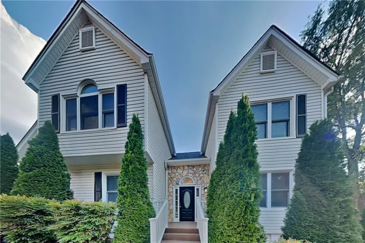 Symmetrical facade featuring twin gables, stone accents, and white siding