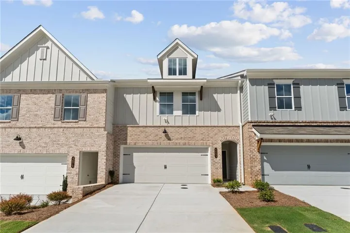 Modern townhome exterior featuring light brick and vertical siding accents