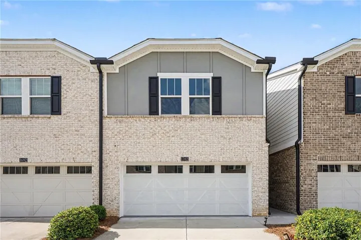 Brick exterior with painted siding accents, black window shutters, and a two-car garage