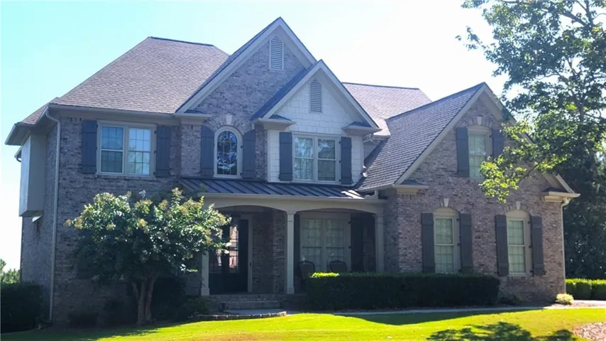 Culdesac lot with level driveway leading to 3 car garage. Two-story brick exterior, covered front porch, arched window accent, gabled roofline, established landscaping. Brick facade with architectural shingles and gable rooflines