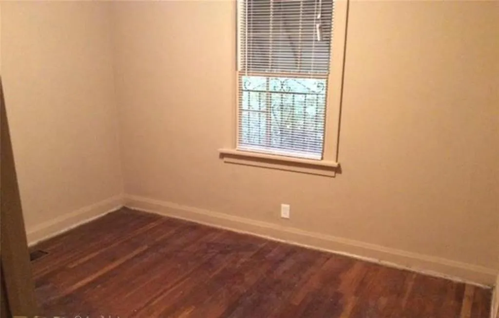 Spare room with baseboards and dark wood-type flooring