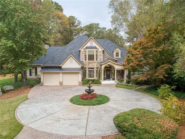Traditional-style home with stone siding, curved driveway, a standing seam roof, and roof with shingles