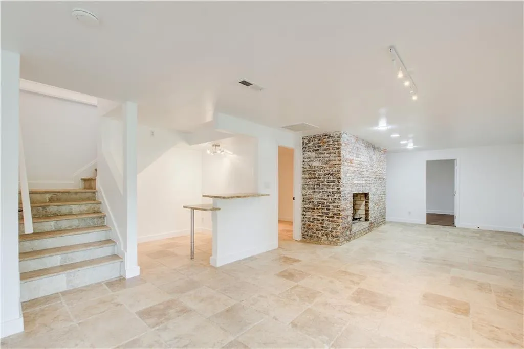 Unfurnished living room featuring stairs, a fireplace, rail lighting, and baseboards