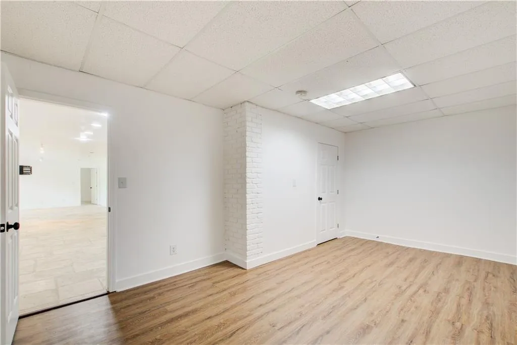 Empty room featuring a paneled ceiling, wood finished floors, baseboards, and a smoke detector