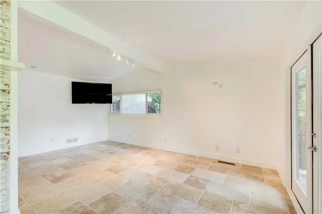 Empty room featuring light stone finish floors, baseboards, and track lighting