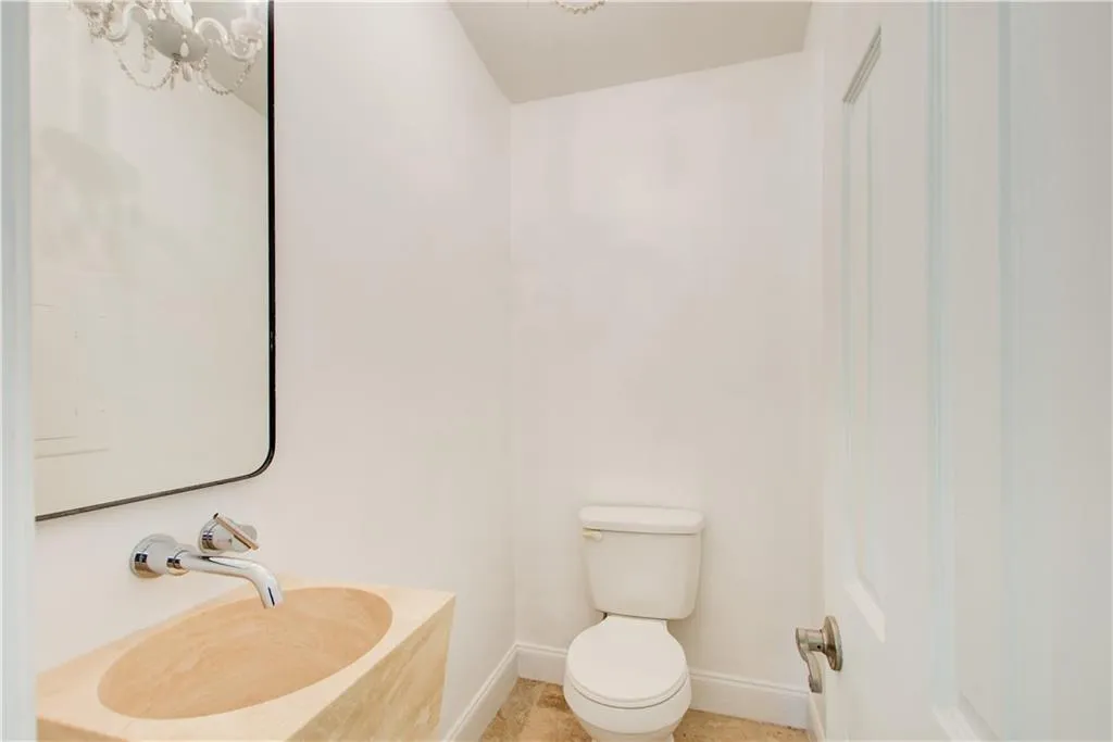Bathroom featuring baseboards, a sink, toilet, and a chandelier