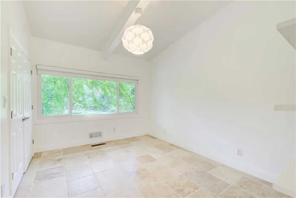 Spare room featuring baseboards and light stone finish flooring
