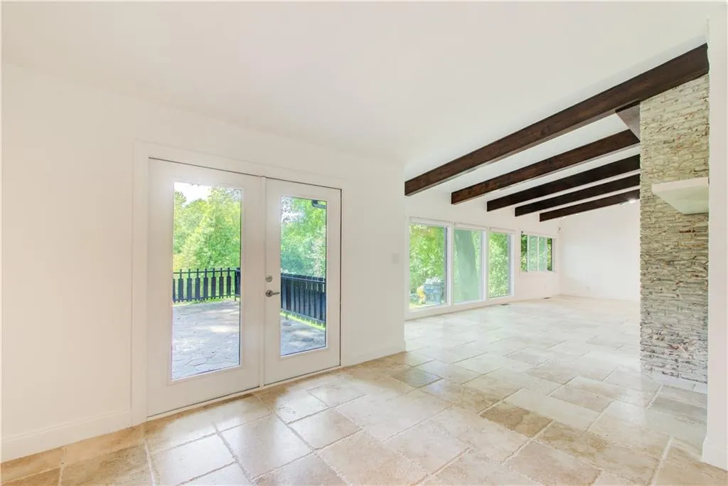 Doorway with french doors, stone tile flooring, baseboards, and beam ceiling