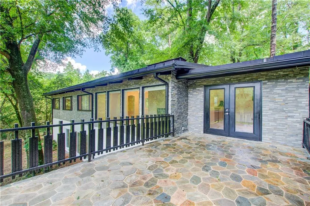 Rear view of property with french doors, stone siding, and a patio area