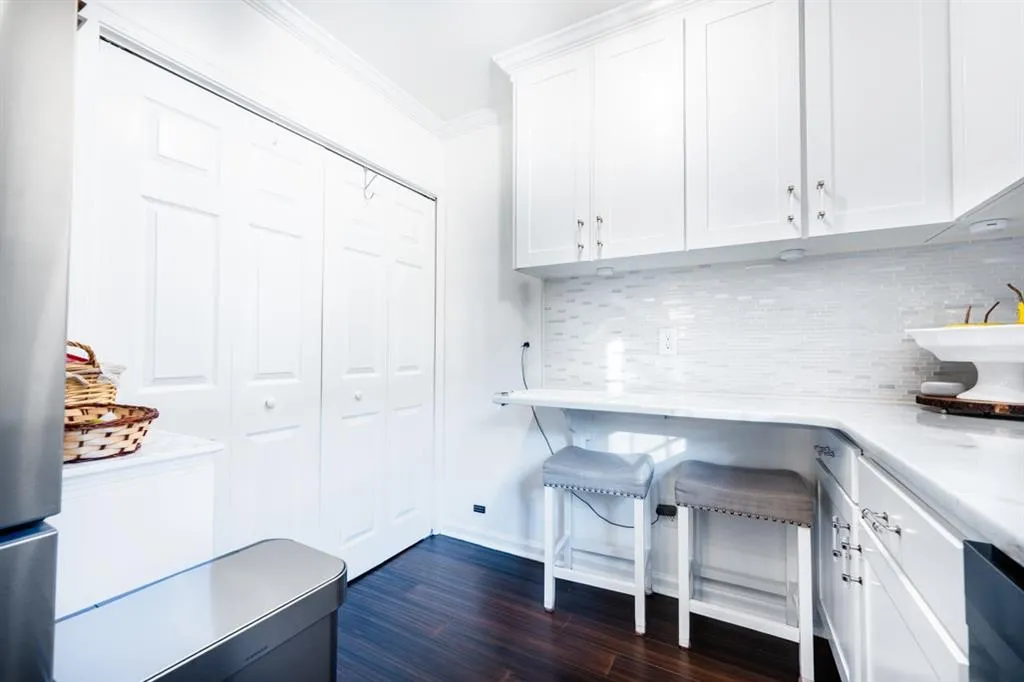 Eat in area with dark wood flooring, white cabinets.