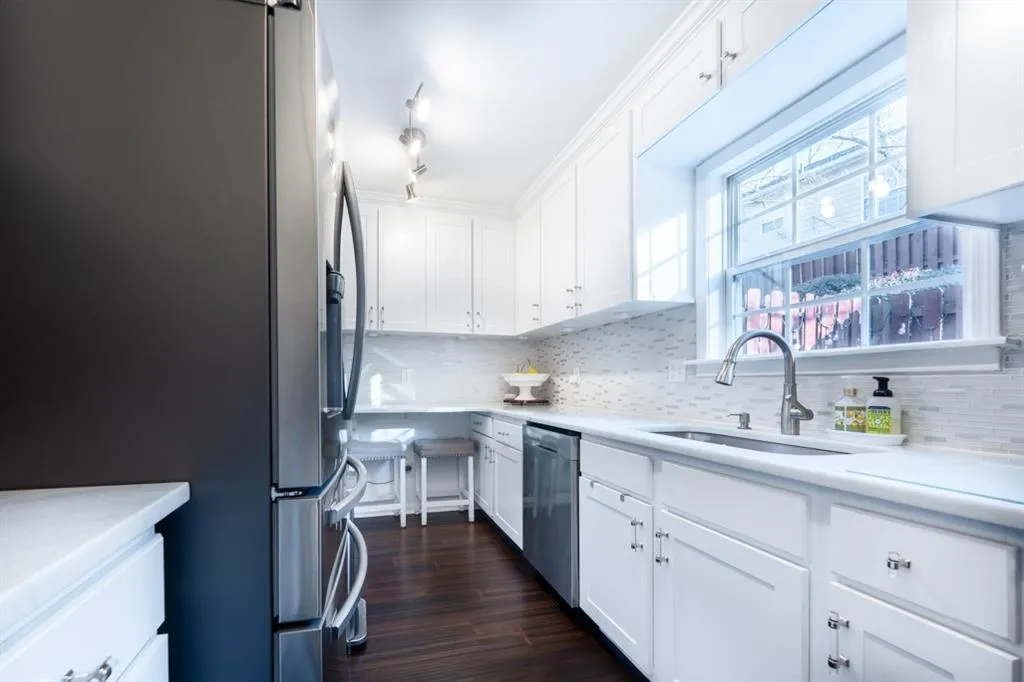 Kitchen with light countertops, appliances with stainless steel finishes, a sink, and white cabinetry