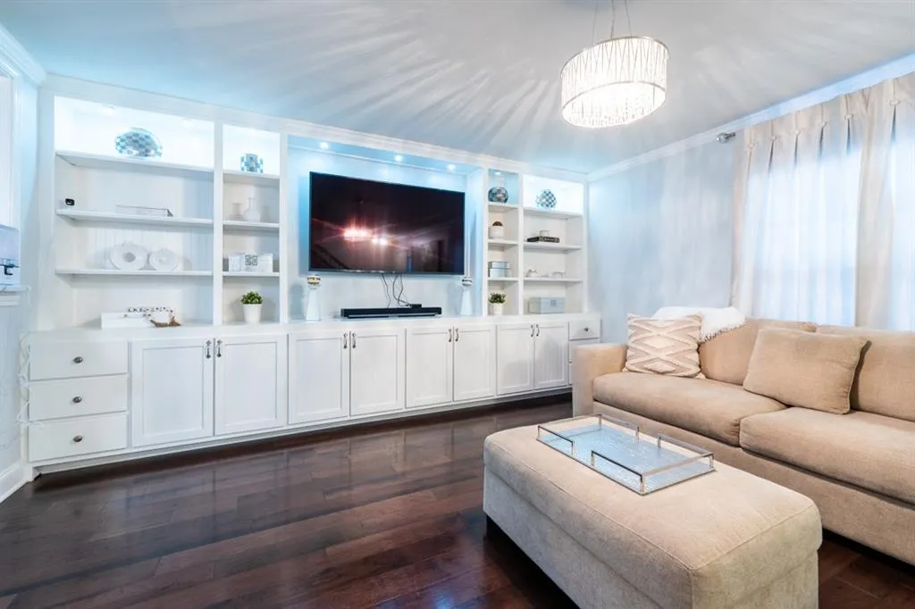 Living area featuring a chandelier, dark wood finished floors, built in features, and crown molding