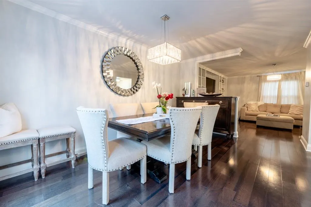 Dining space with ornamental molding, dark wood-type flooring, and an inviting chandelier