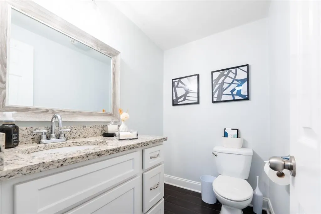 Half Bathroom featuring toilet, wood finished floors, vanity, and baseboards