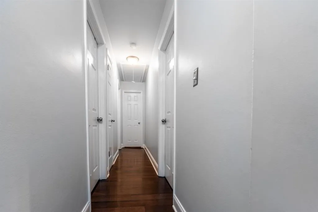 Hallway with attic access, baseboards, and dark wood-type flooring