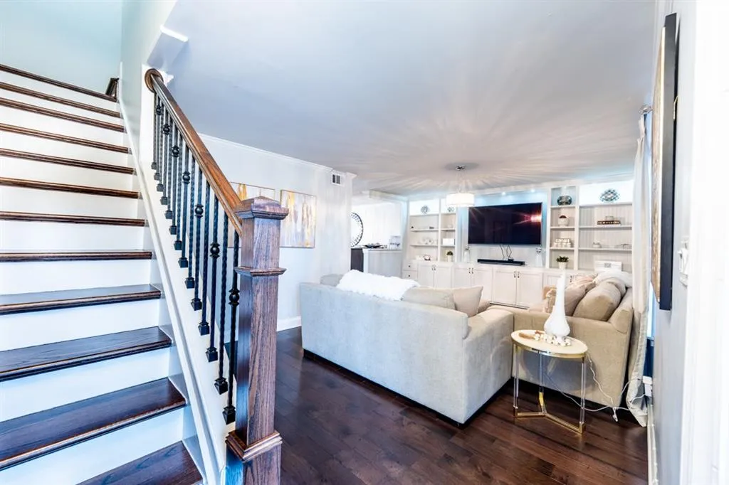 Living room featuring built in features, visible vents, dark wood-type flooring, stairs, and crown molding